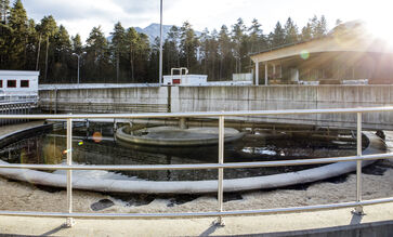 The picture shows a round concrete / steel structure with railing placed on the ground at the site of the sewage treatment plant.