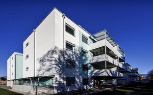 The picture shows a modern residential complex with spacious terraces and white facades.