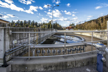 The picture shows a round concrete / steel structure with railing placed on the ground at the site of the sewage treatment plant.