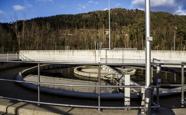 The picture shows a round concrete / steel structure with railing placed on the ground at the site of the sewage treatment plant.