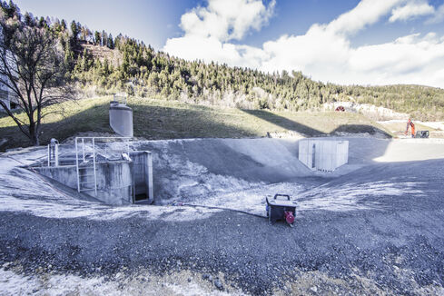 The picture shows a deepened accumulation of water, surrounded by light shingle and gravel, with two concrete structures at the top and bottom.