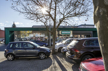 Nell'immagine si vede il portale d'ingresso incorniciato da una costruzione verde con un frontale in vetro molto esteso in lunghezza.