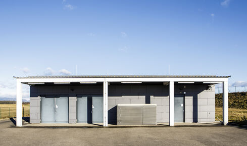 The picture shows an elongated, flat building in an open terrain with three entrances to the complex.