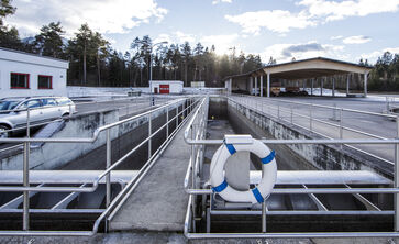 The picture shows a round concrete / steel structure with railing placed on the ground at the site of the sewage treatment plant.