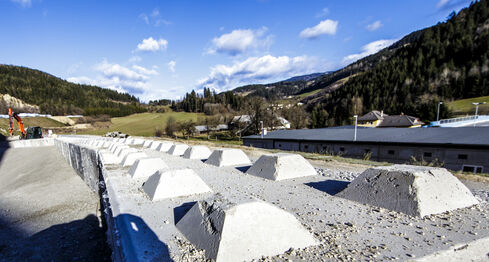 The picture shows a deepened accumulation of water, surrounded by light shingle and gravel, with two concrete structures at the top and bottom.