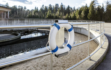 The picture shows a round concrete / steel structure with railing placed on the ground at the site of the sewage treatment plant.