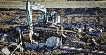 The picture shows a large construction site with heavy equipment in the field.
