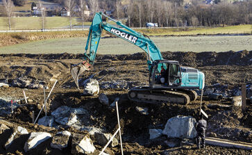 Nell'immagine si vede un grande cantiere con mezzo pesante in un campo.