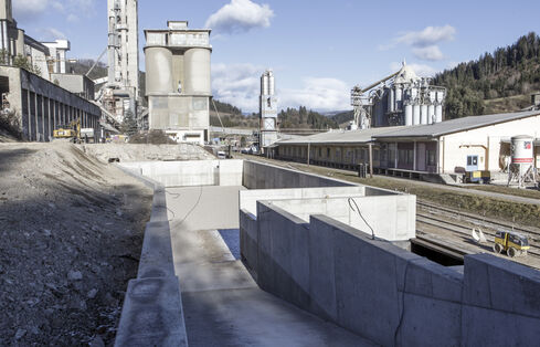 The picture shows a deepened accumulation of water, surrounded by light shingle and gravel, with two concrete structures at the top and bottom.